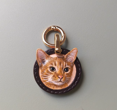 Custom-made luxury leather pet keepsakes and gifts featuring pet portraits, including cat and dog keychains.