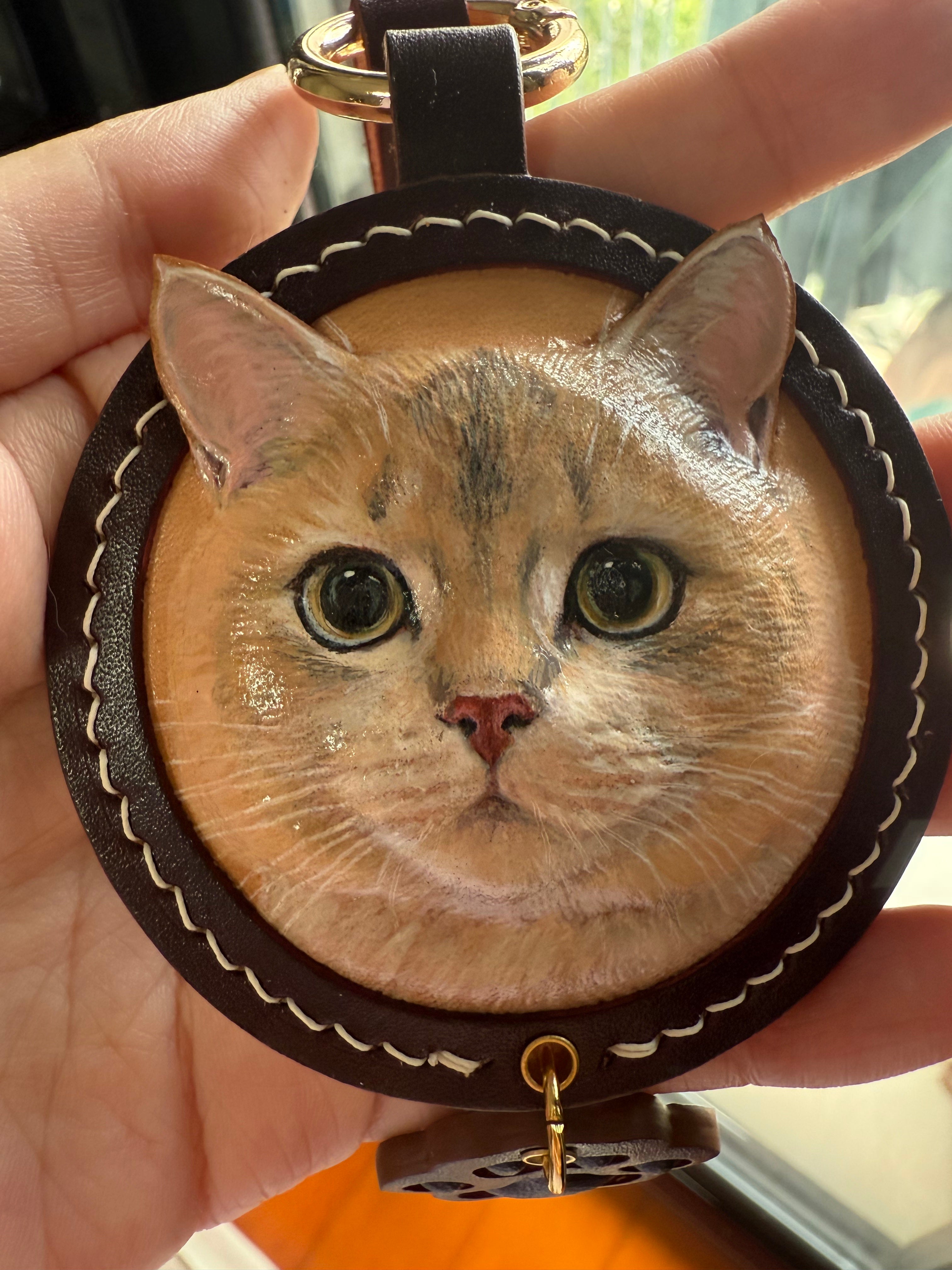 Custom-made luxury leather pet keepsakes and gifts featuring pet portraits, including cat and dog keychains.